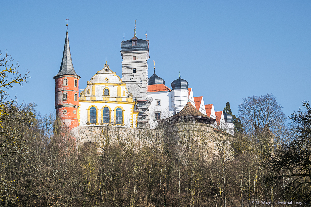 Schlossanlage mit Tuermen, Giebeln und Wehrmauer am bewachsenen Hang mit blauem Himmel - Denkmalfotografie